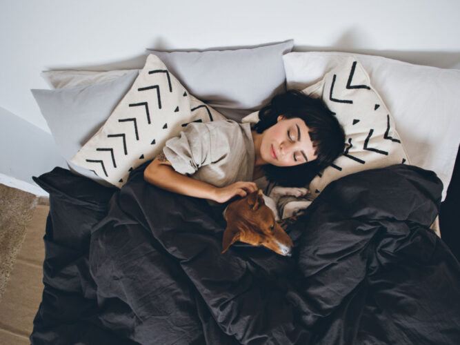 woman sleeping in bed with dog
