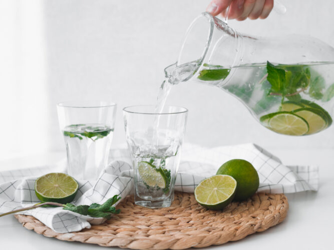 pouring lime and herb infused water into a glass