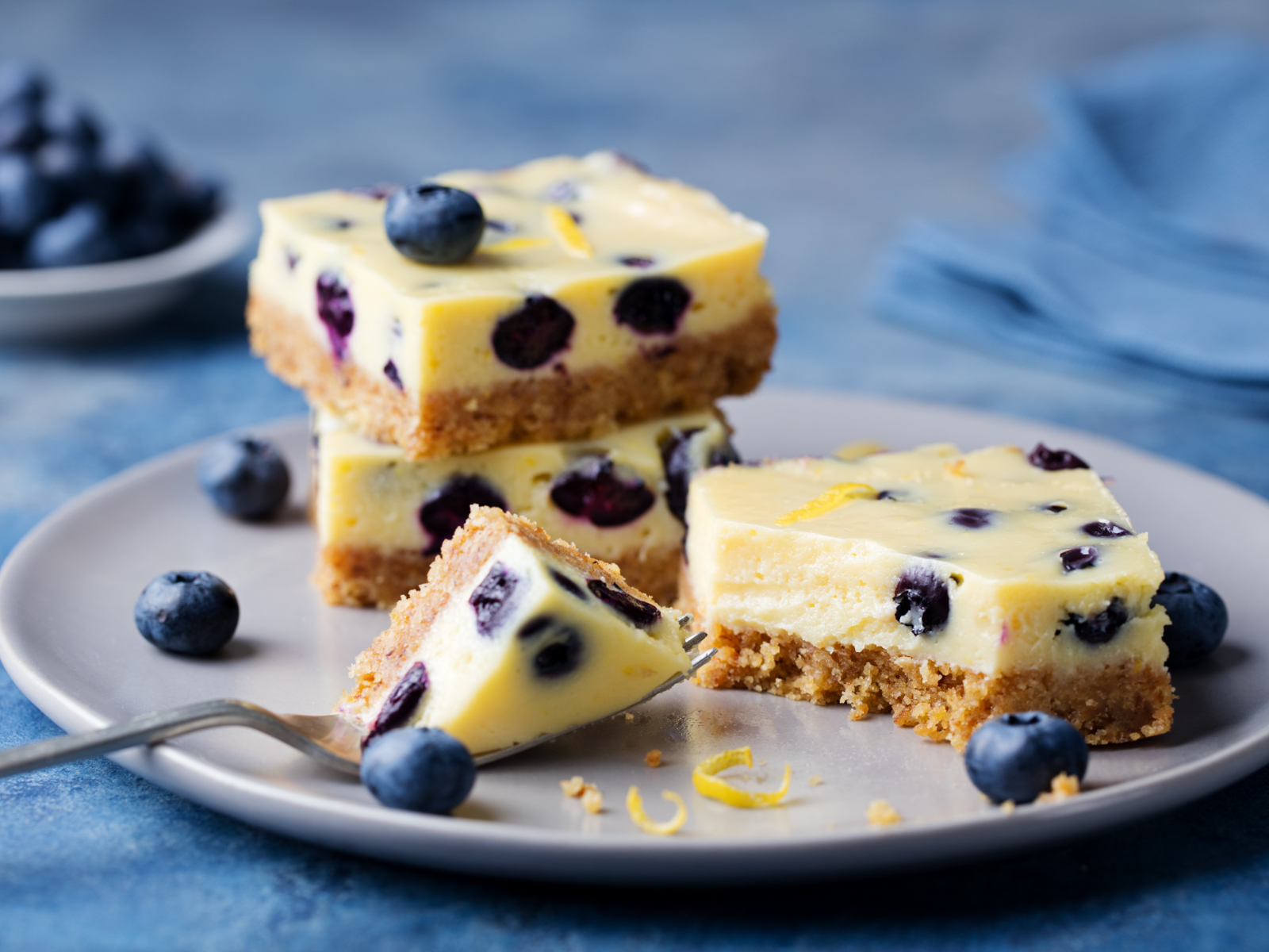 blueberry lemon cheesecake bars stacked on a plate