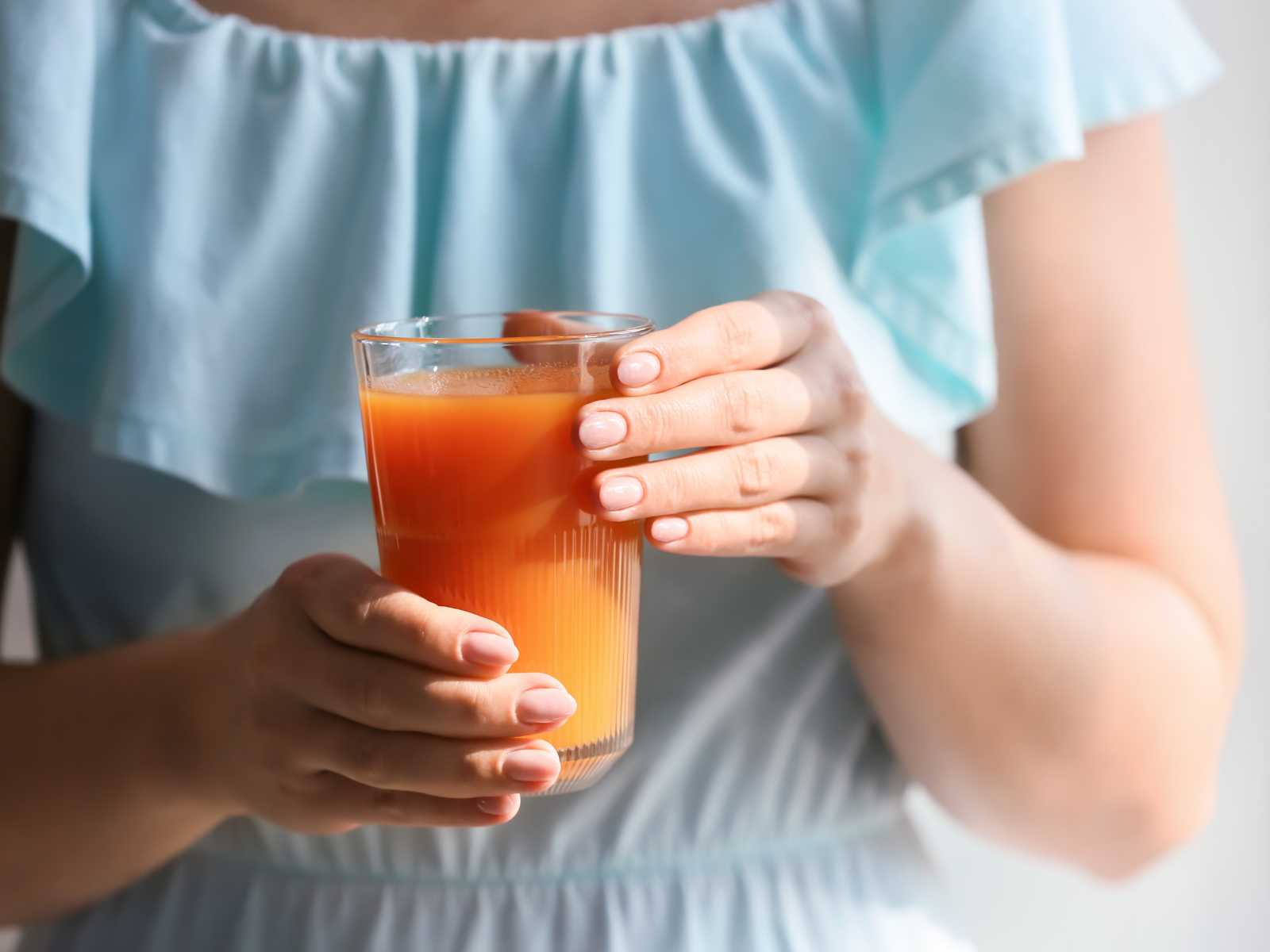 woman holding glass of carrot juice