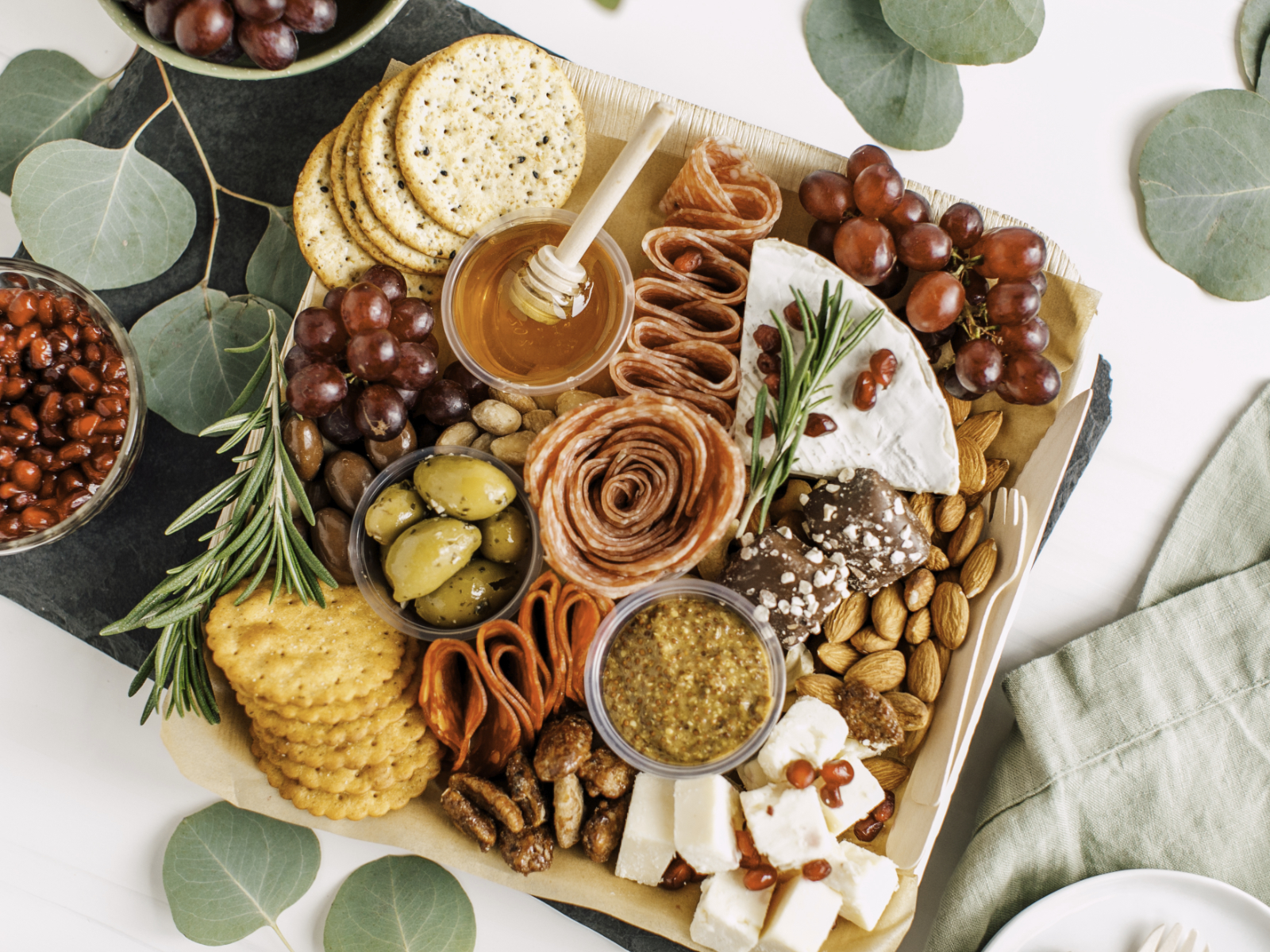 charcuterie board with crackers meat fruit and honey