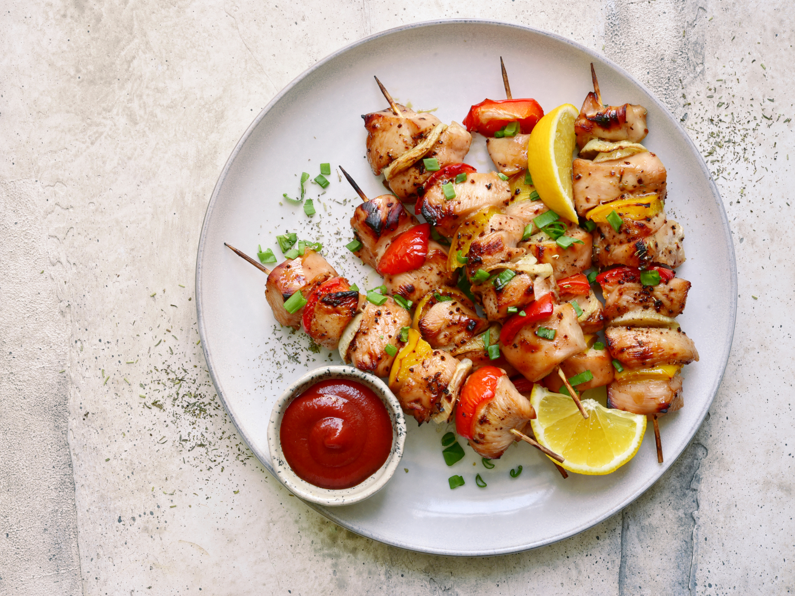 chicken and vegetable skewers with lemon wedges and a side of ketchup