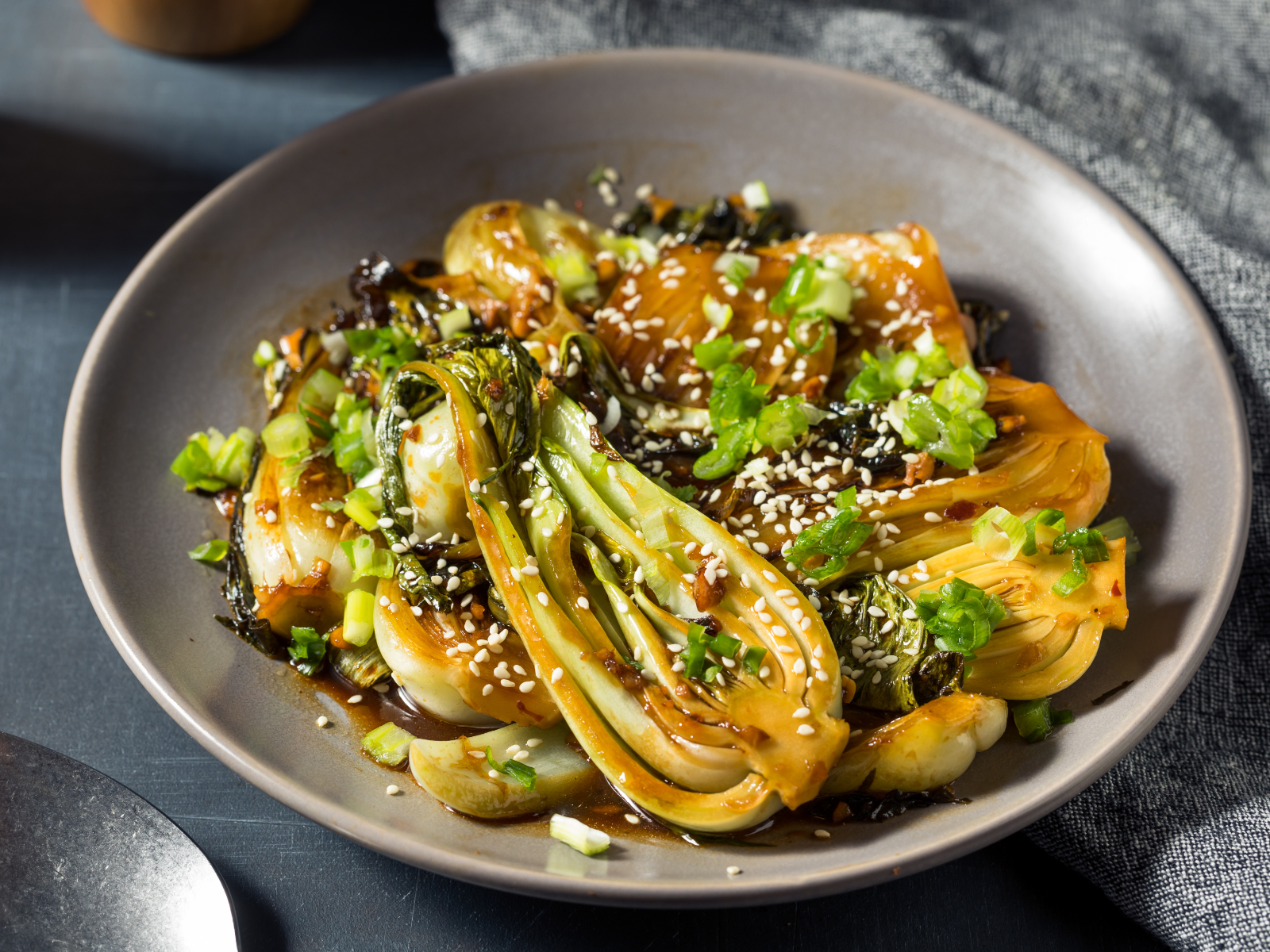 cooked bok choy in a bowl with glaze and sesame seeds