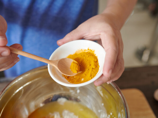 person holding small bowl of ground turmeric to add in a recipe