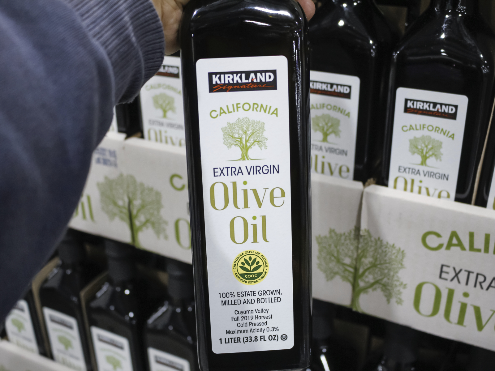 costco shopper holding a bottle of olive oil
