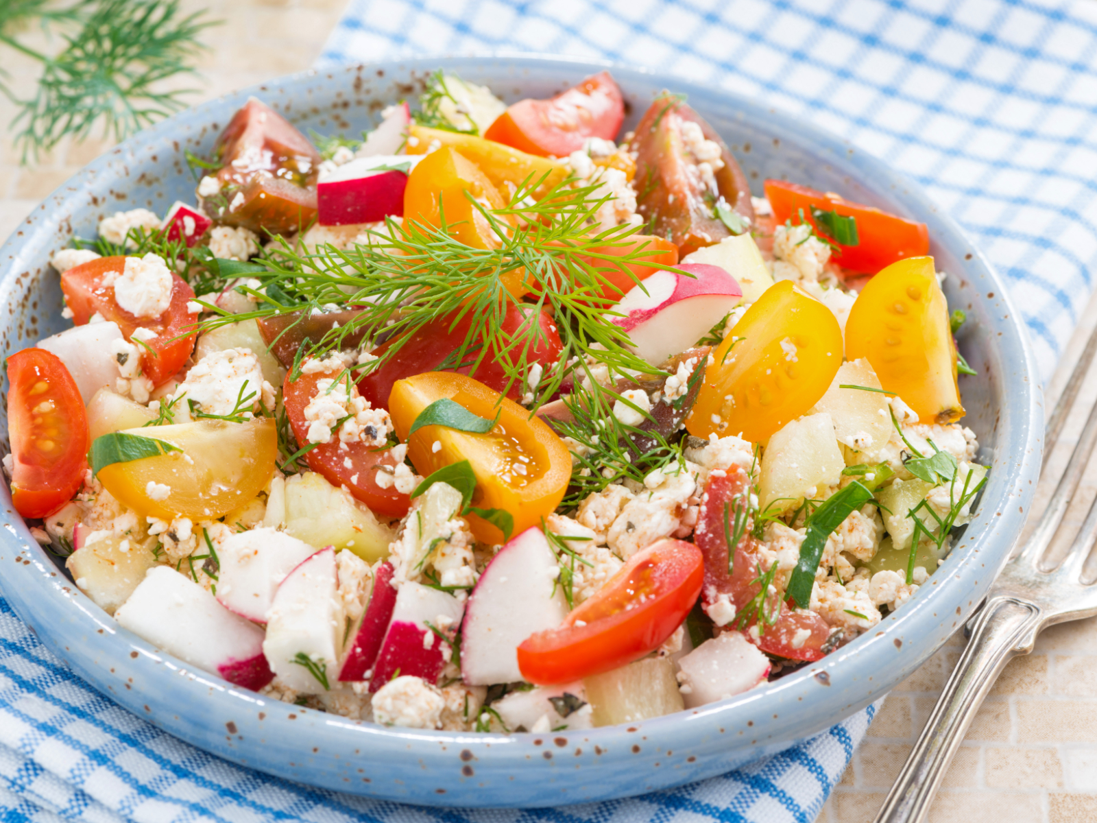 cottage cheese salad with cherry tomatoes, cucumbers, dressing, and fresh herbs