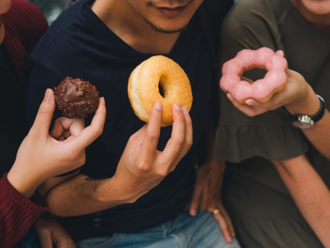 three people eating sugary donuts
