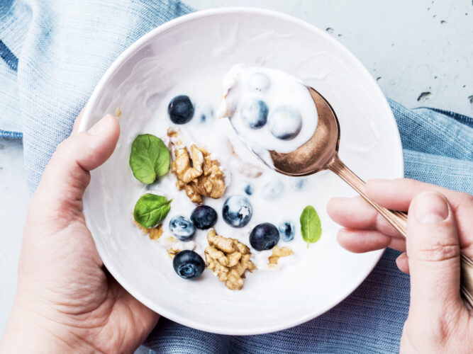 digging into a bowl of yogurt with blueberries and walnuts