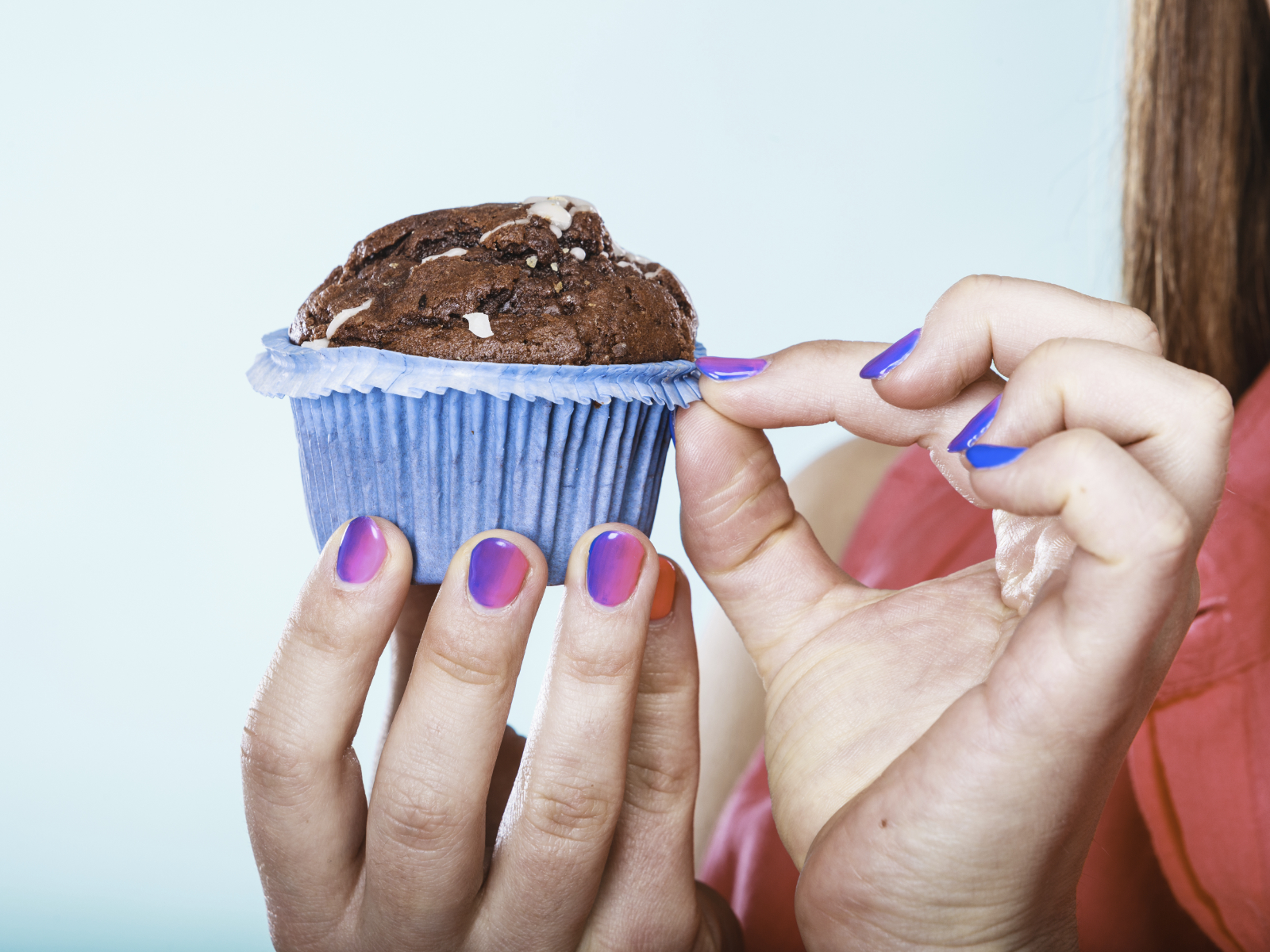 woman unwrapping a chocolate muffin