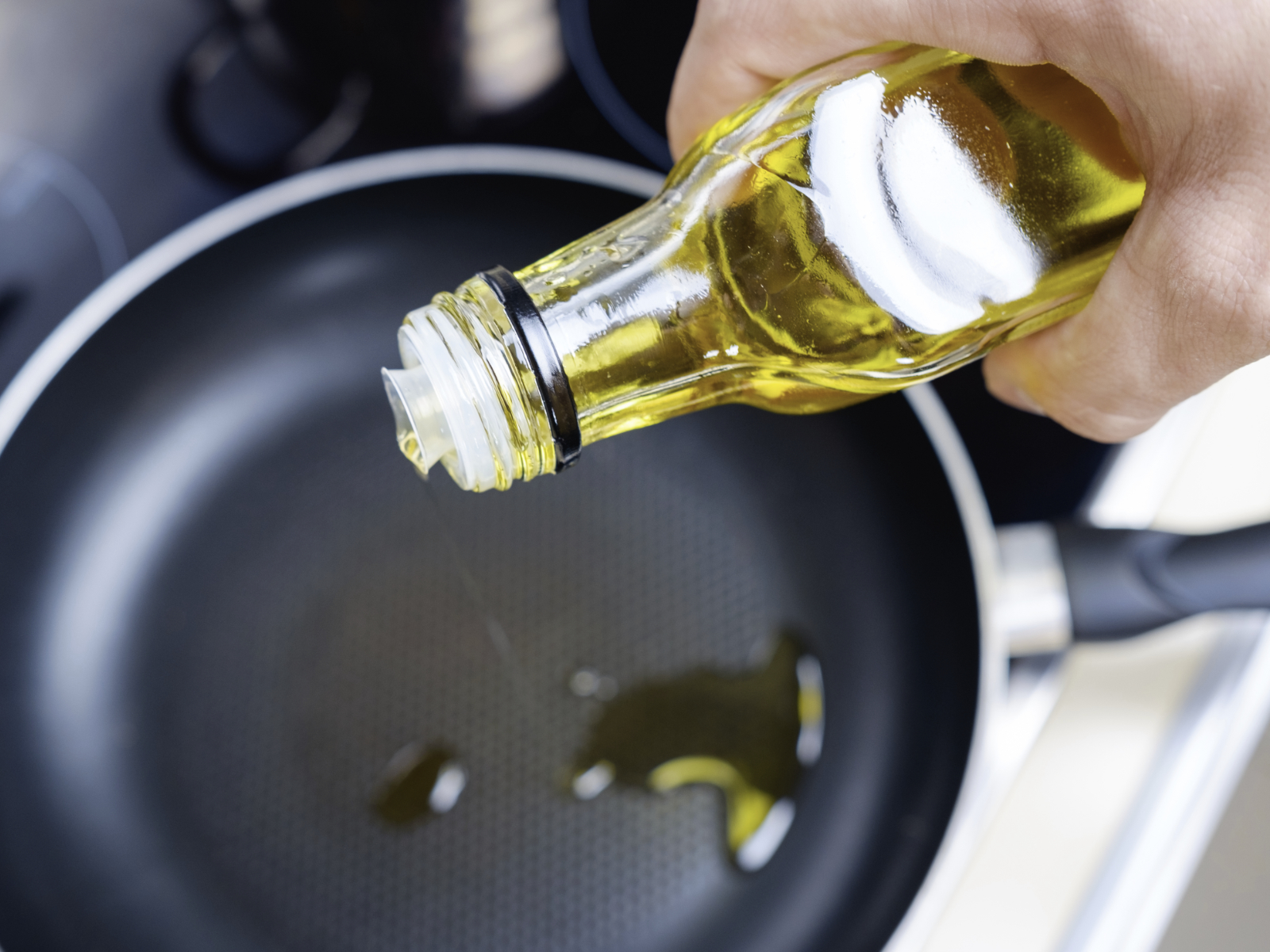 pouring olive oil onto a hot pan