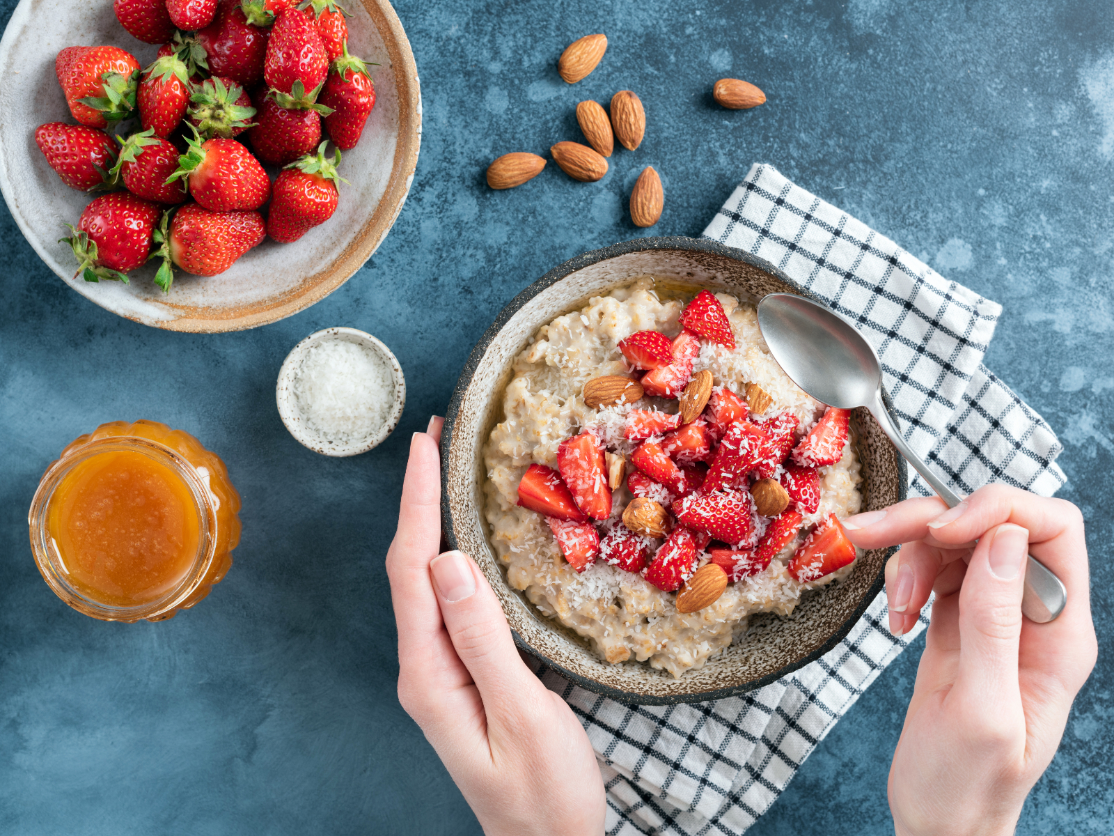 woman holding bowl of oatmeal with strawberries and almonds