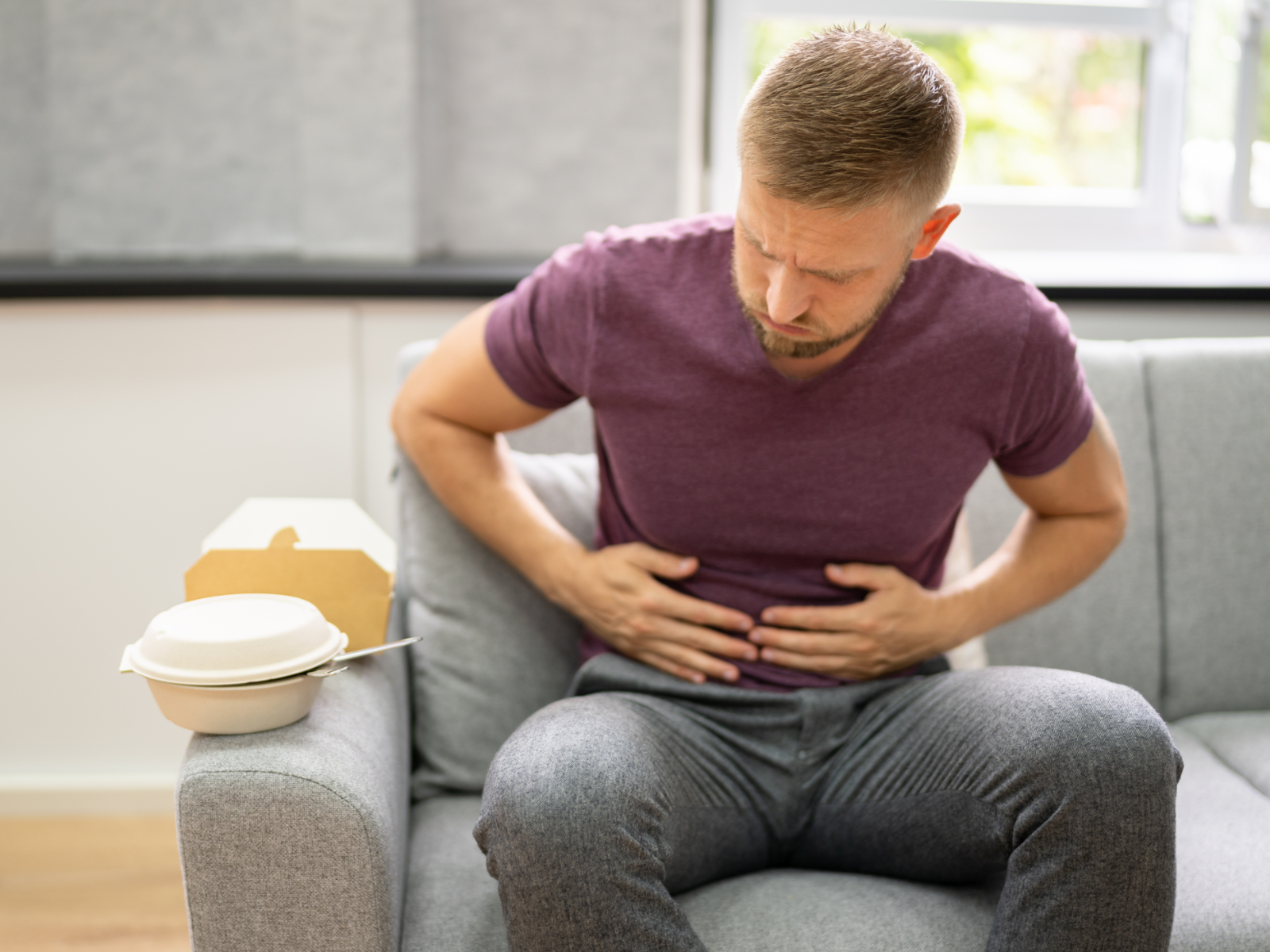 man holding an upset stomach after eating spicy fast food