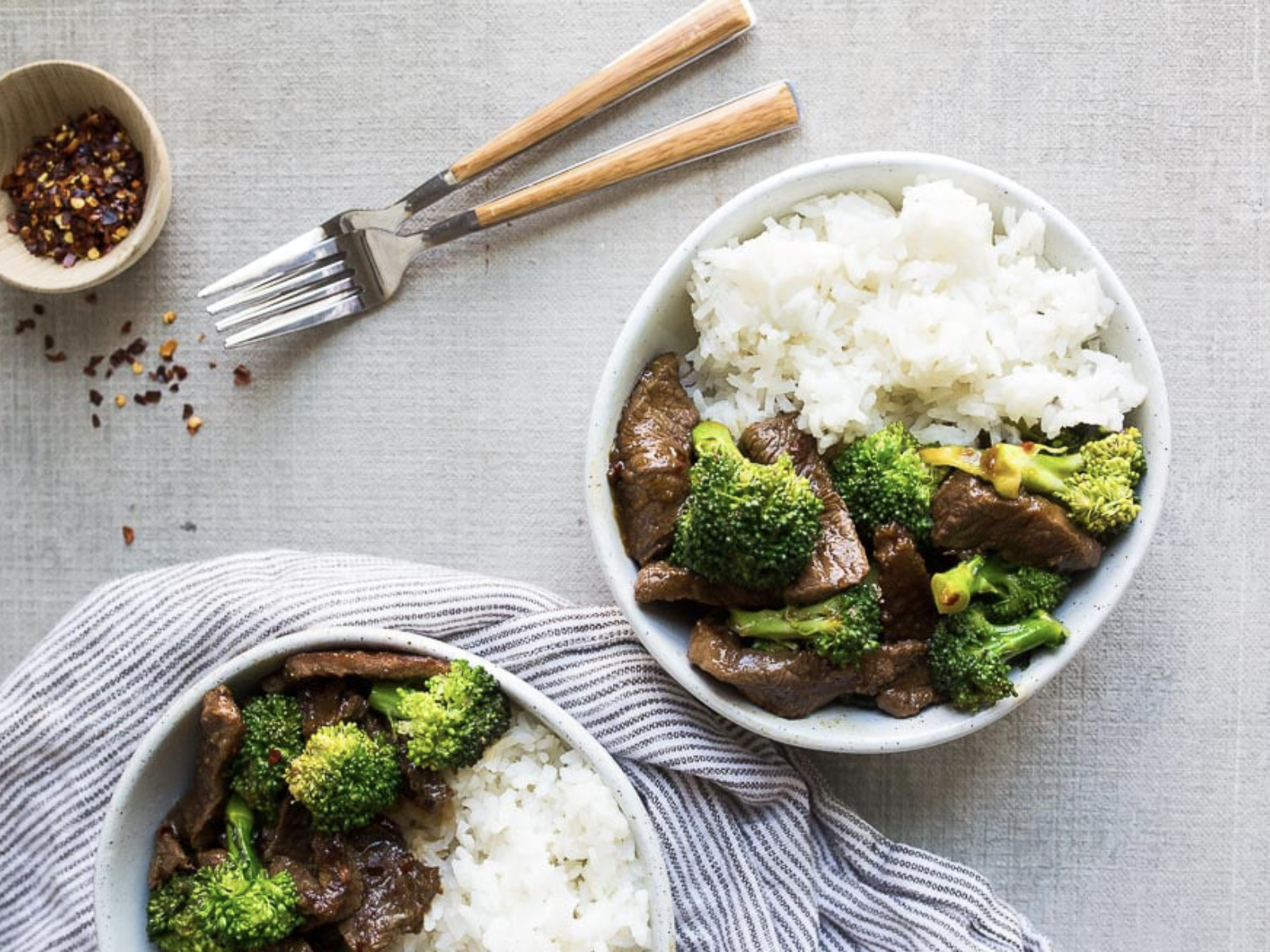 bowls of frozen broccoli and beef stir fry with rice and red pepper flakes