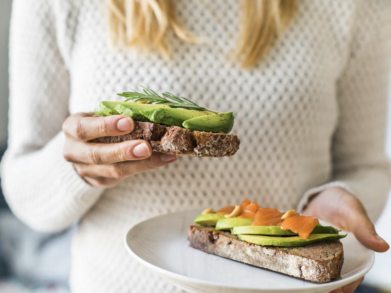 woman holding gut healthy foods whole grain toast with avocado and salmon