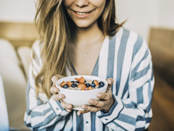 woman holding healthy bowl with blueberries and strawberries