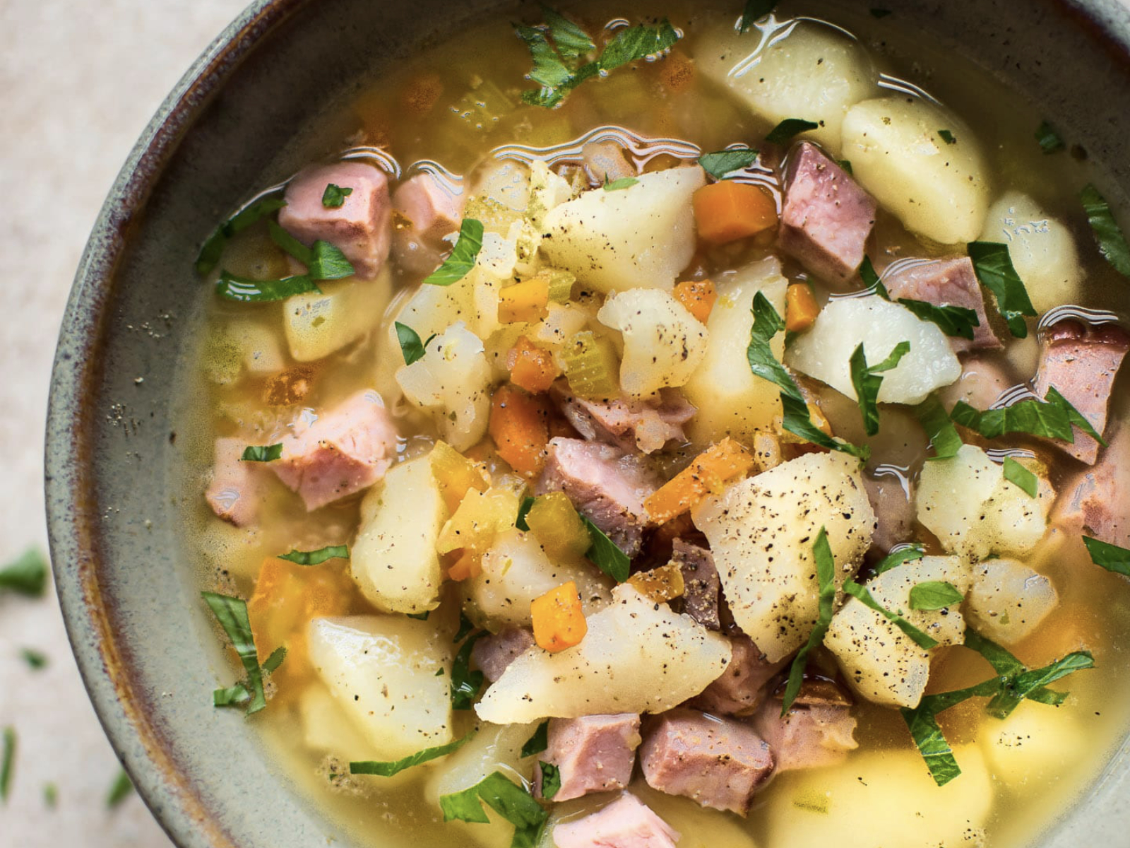 ham and potato crock pot soup in a bowl with fresh herbs