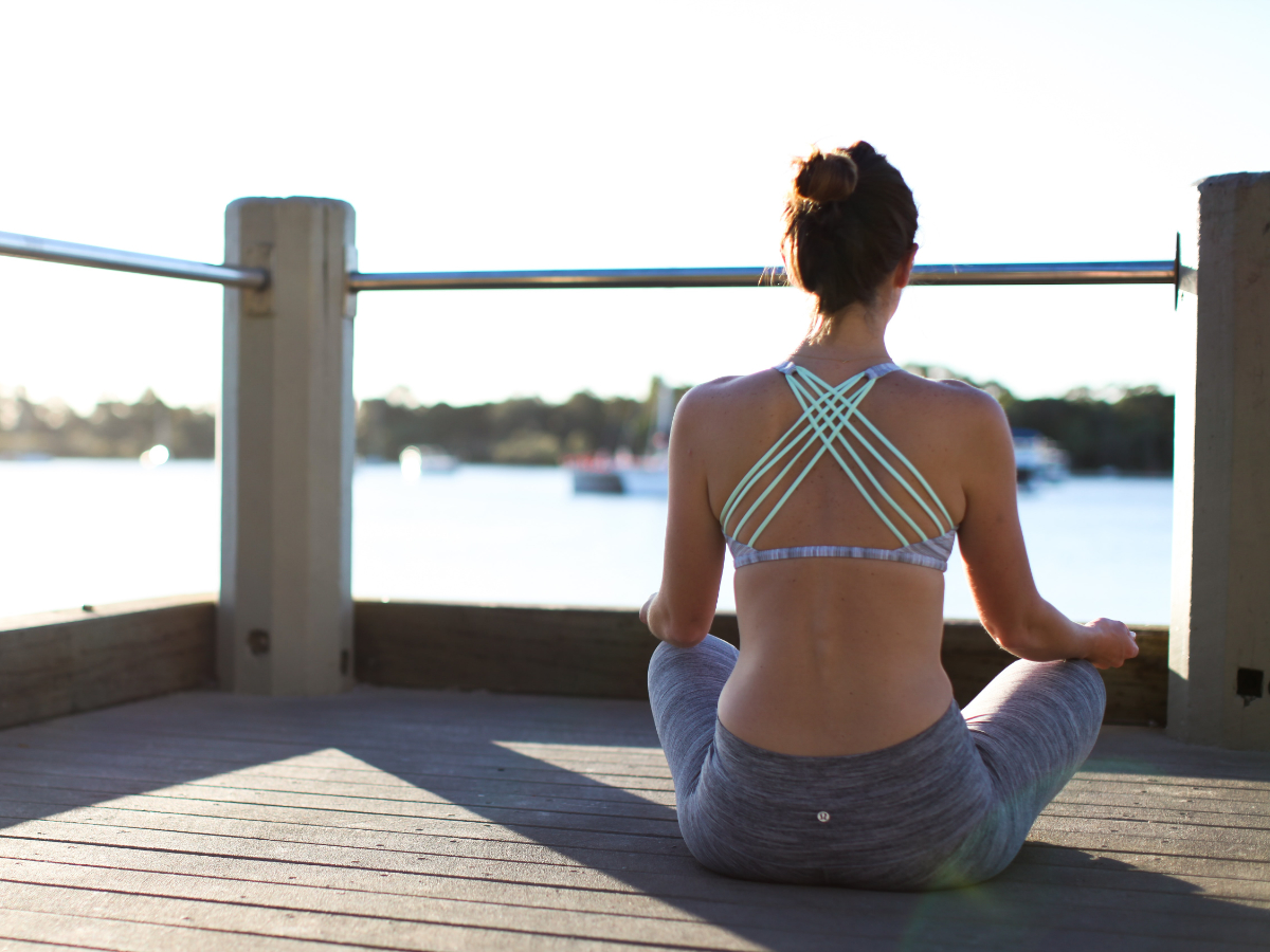 healthy woman meditating on a dock