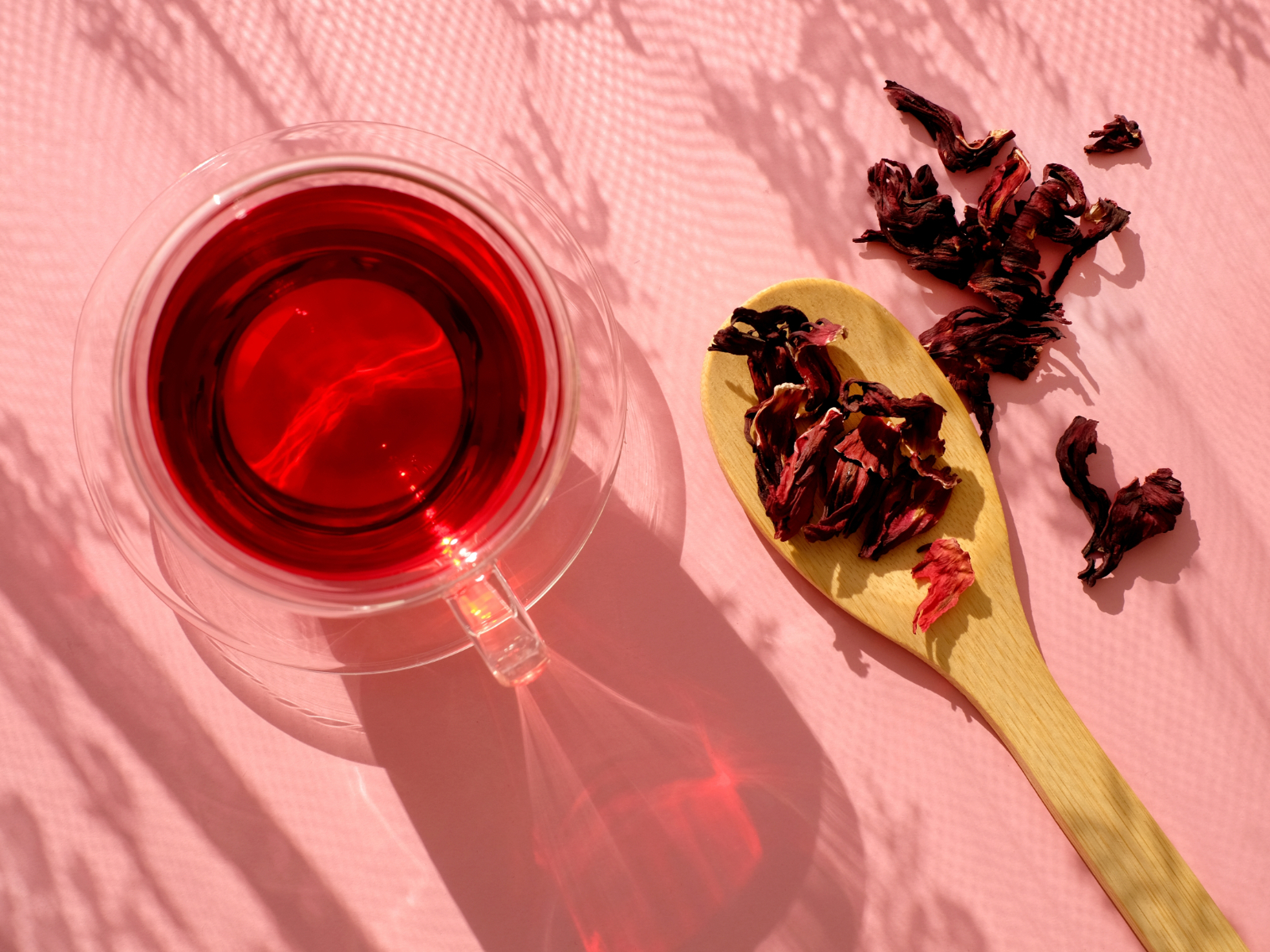 cup of hibiscus tea next to a spoonful of loose tea