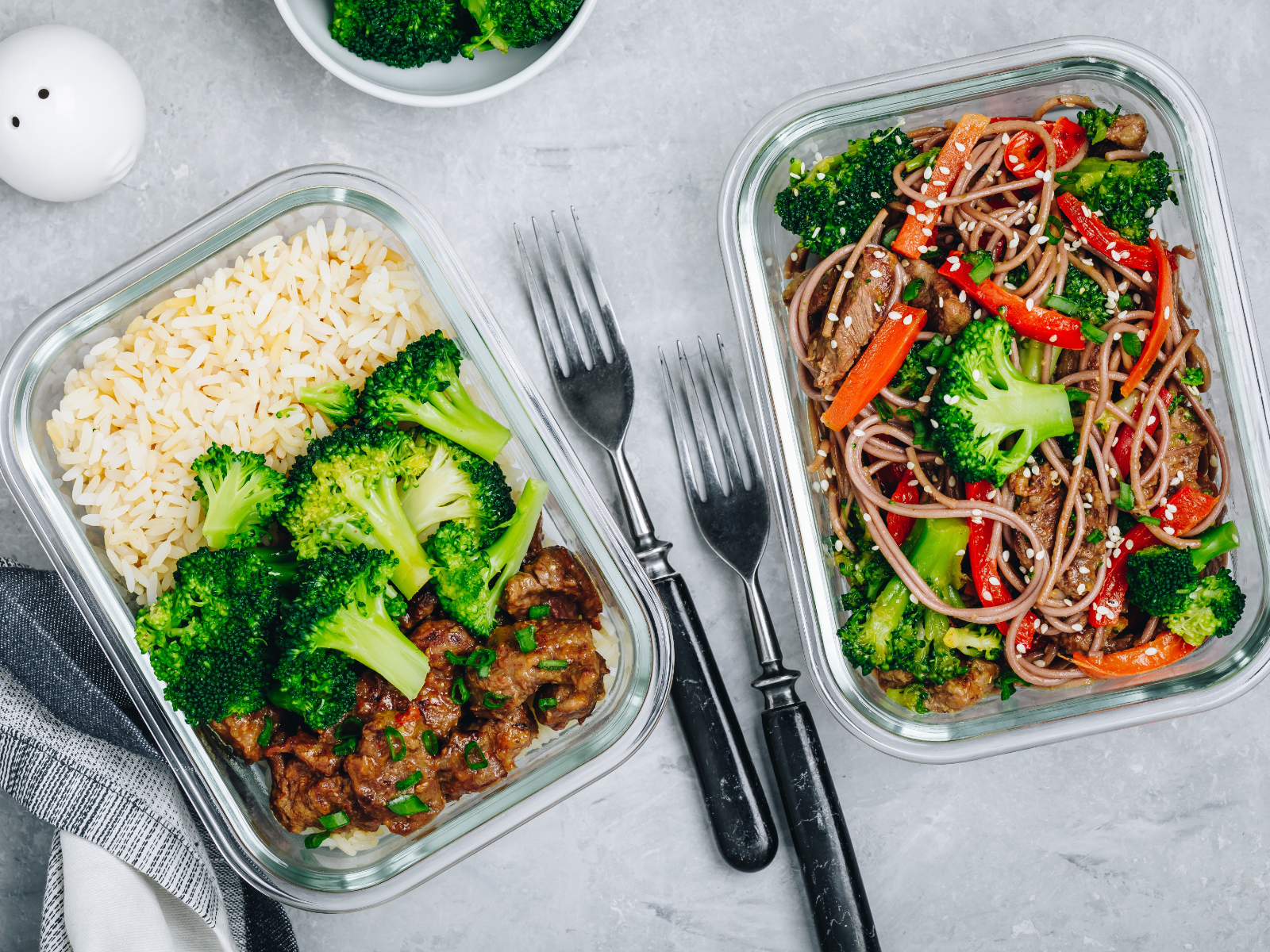 meal prep containers with beef broccoli stir fry and a noddle stir fry