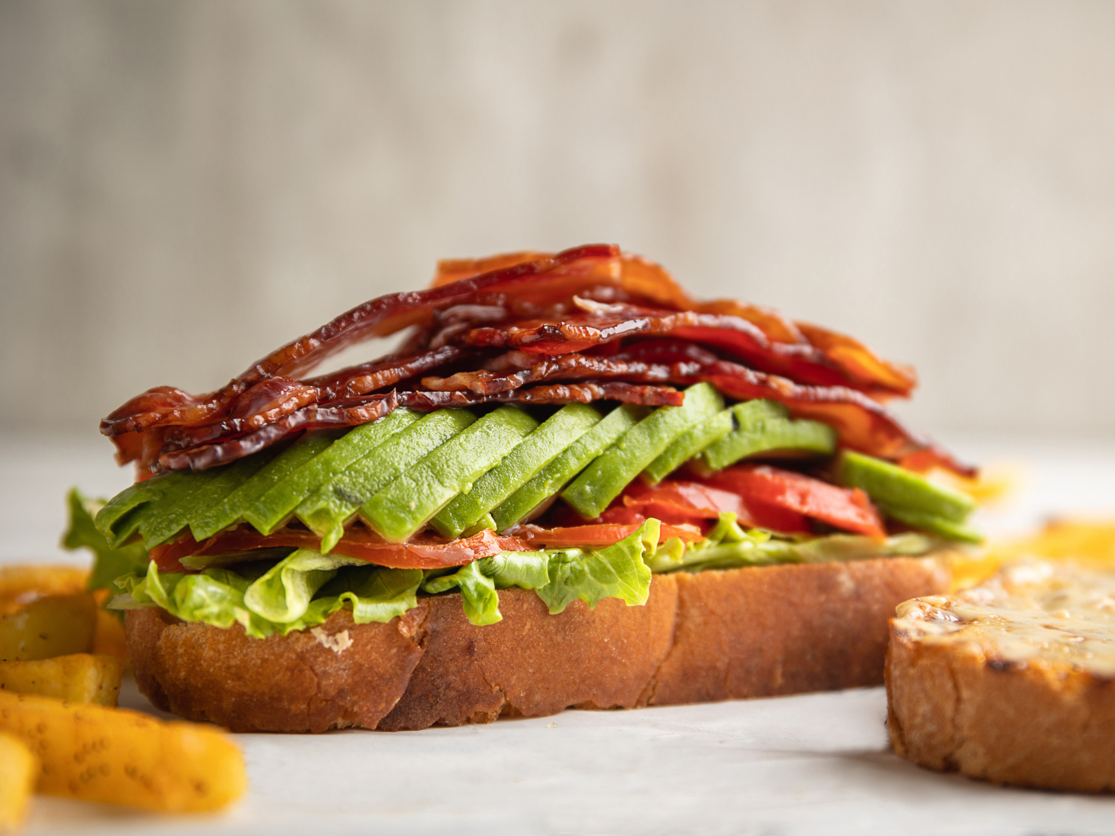 turkey bacon BLT with avocado slices on a slice of bread