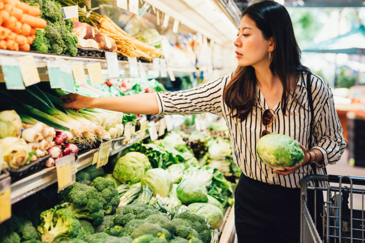 woman reaching for produce at grocery store