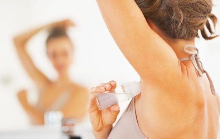 Closeup on woman applying roller deodorant on underarm