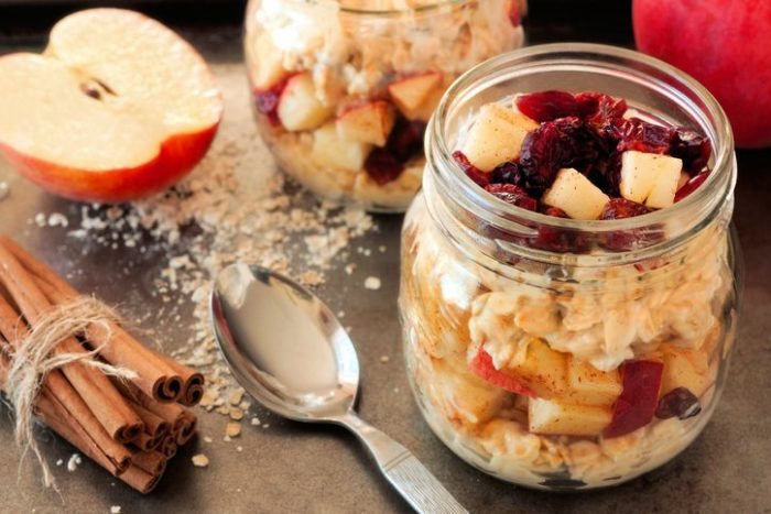Autumn overnight oats with apples and cranberries in a mason jar on vintage metal background