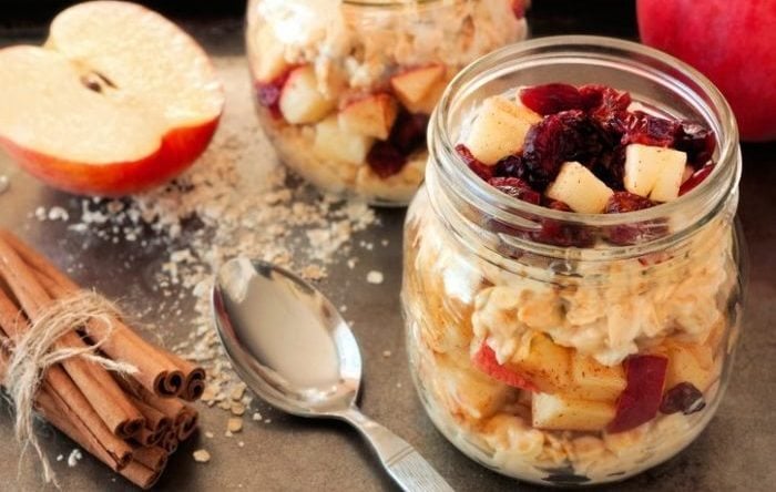 Autumn overnight oats with apples and cranberries in a mason jar on vintage metal background