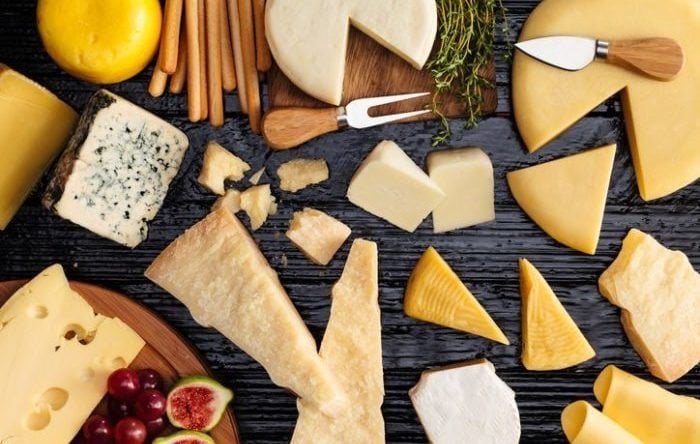 Top view of a dark table filled with a wide variety of cheeses