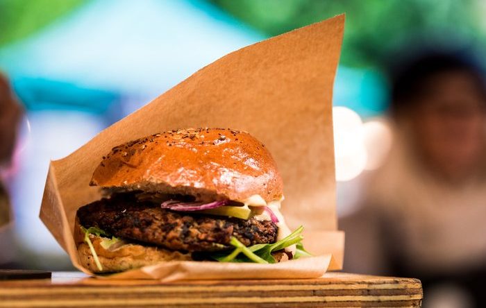 Close up image of a vegan burger on a market stall at the famous Borough Market in London, UK. Extremely shallow depth of field with lights and the commotion of the busy market blurred out of focus in the background. Horizontal colour image with copy space.