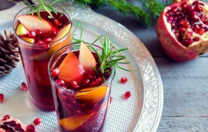 Christmas, autumn or winter sangria with oranges, apples, pomegranate seeds, rosemary and spices - homemade festive drink for Christmas time