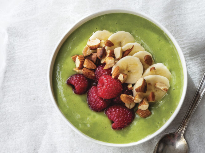 Green Tea Smoothie Bowl with Raspberries almonds and bananas on top