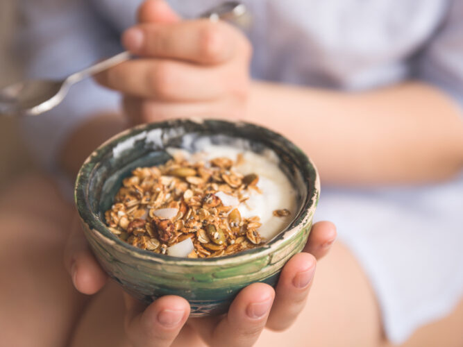 person eating a bowl of greek yogurt with granola