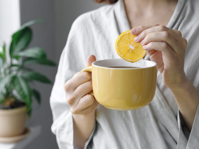 woman adding lemon slice to her morning cup of coffee