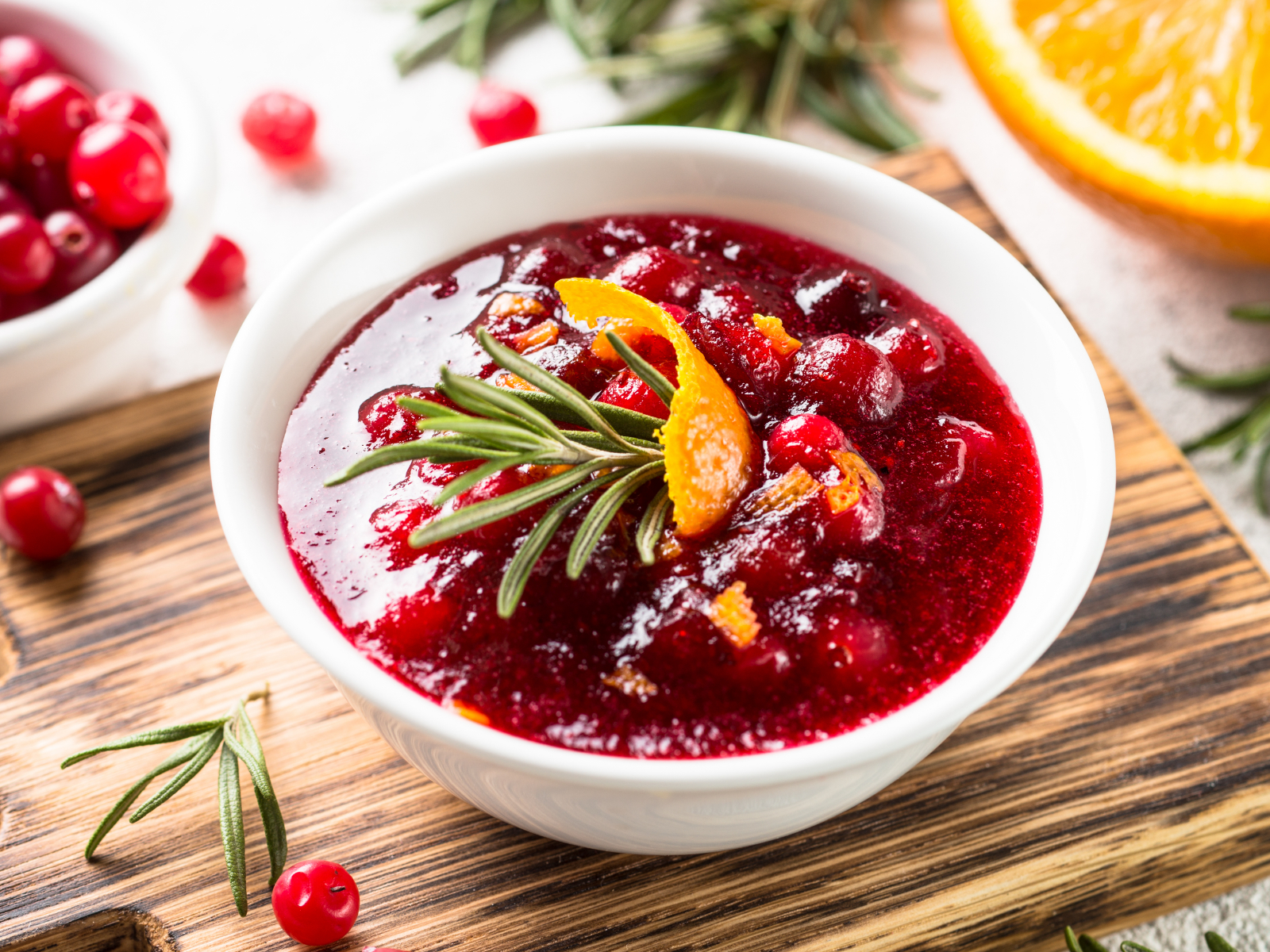 a bowl of low sugar cranberry sauce with orange rinds and rosemary