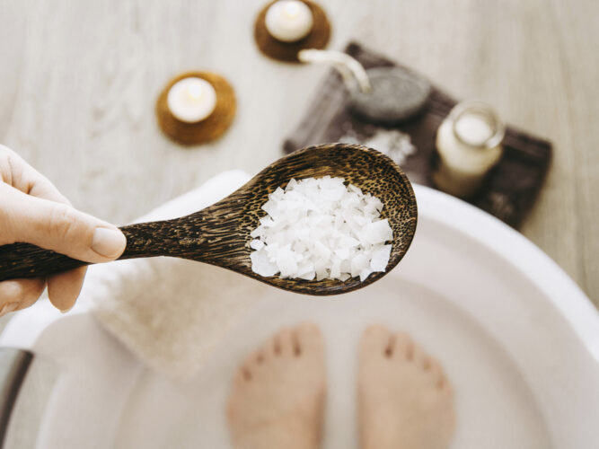 spoonful of magnesium flakes with feet in a bath