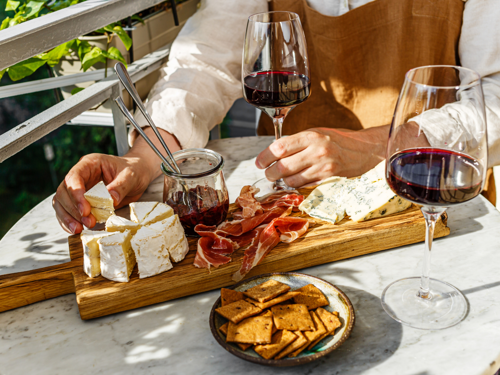 person reaching for cheese on a cheese board