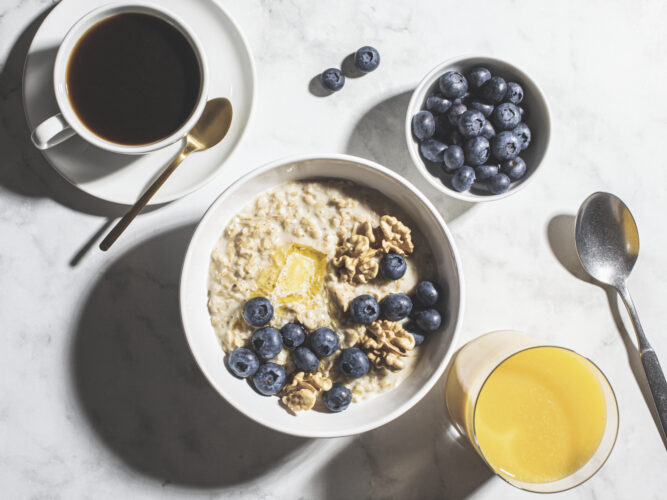 bowl of oatmeal with fruit with coffee and citrus juice
