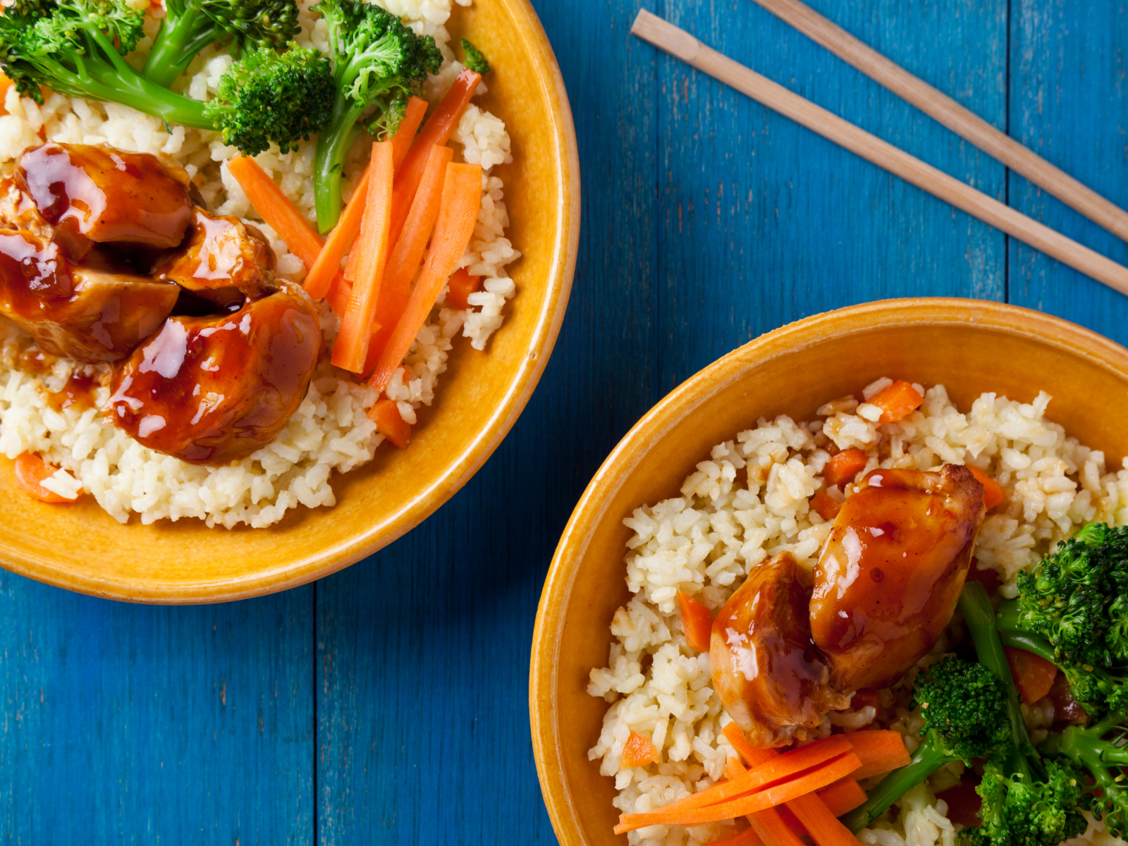 orange chicken in a rice bowl with veggies
