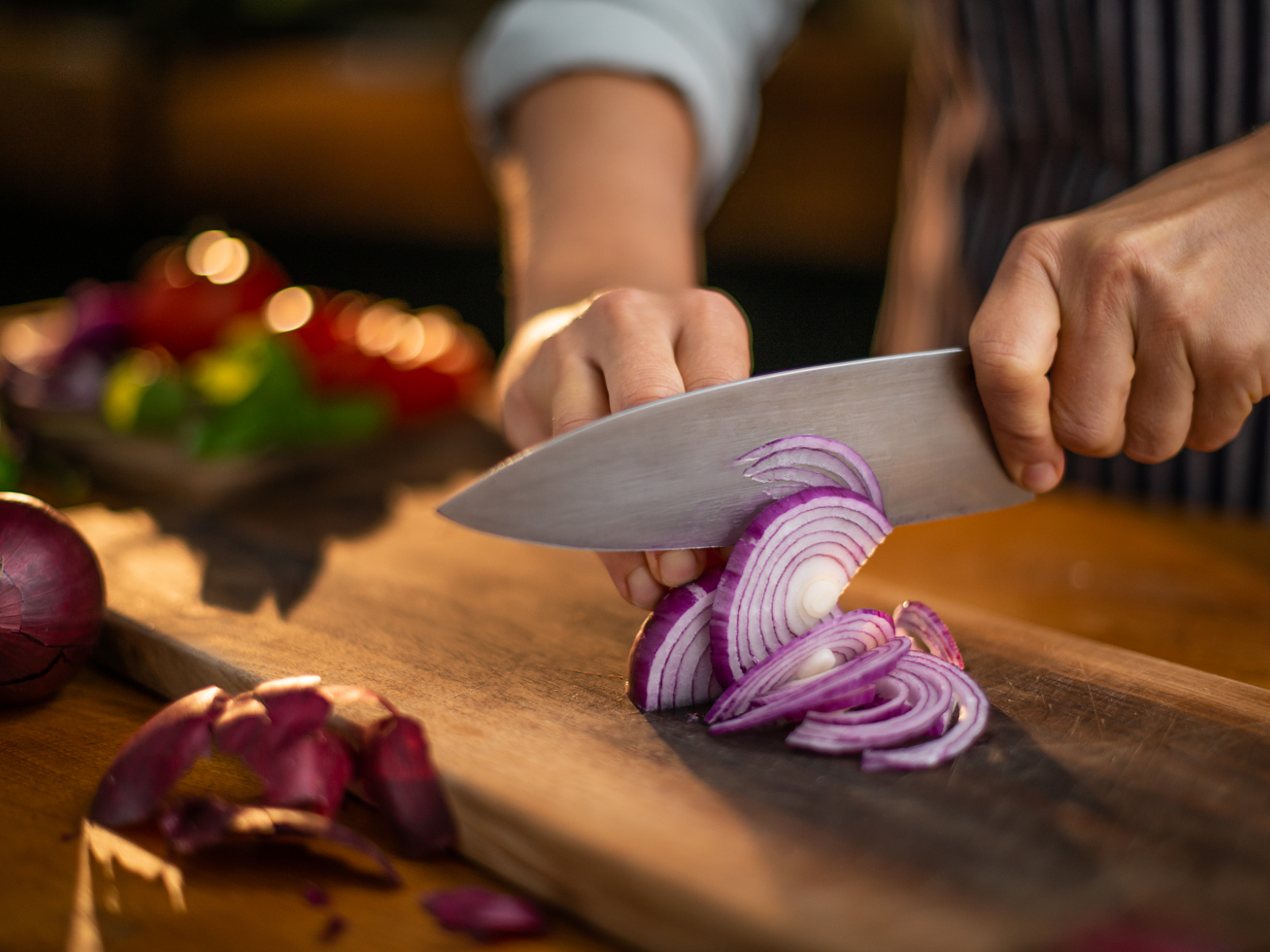slicing a red onion on a cutting board