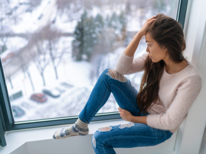 woman looking sad looking out a window