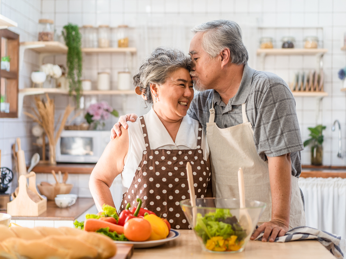 An older couple happily preparing food in their kitchen