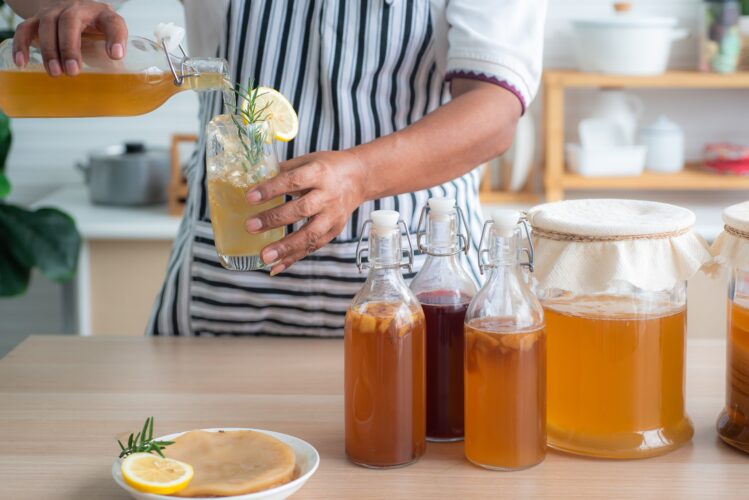 chef pouring bottle of homemade kombucha into a cup