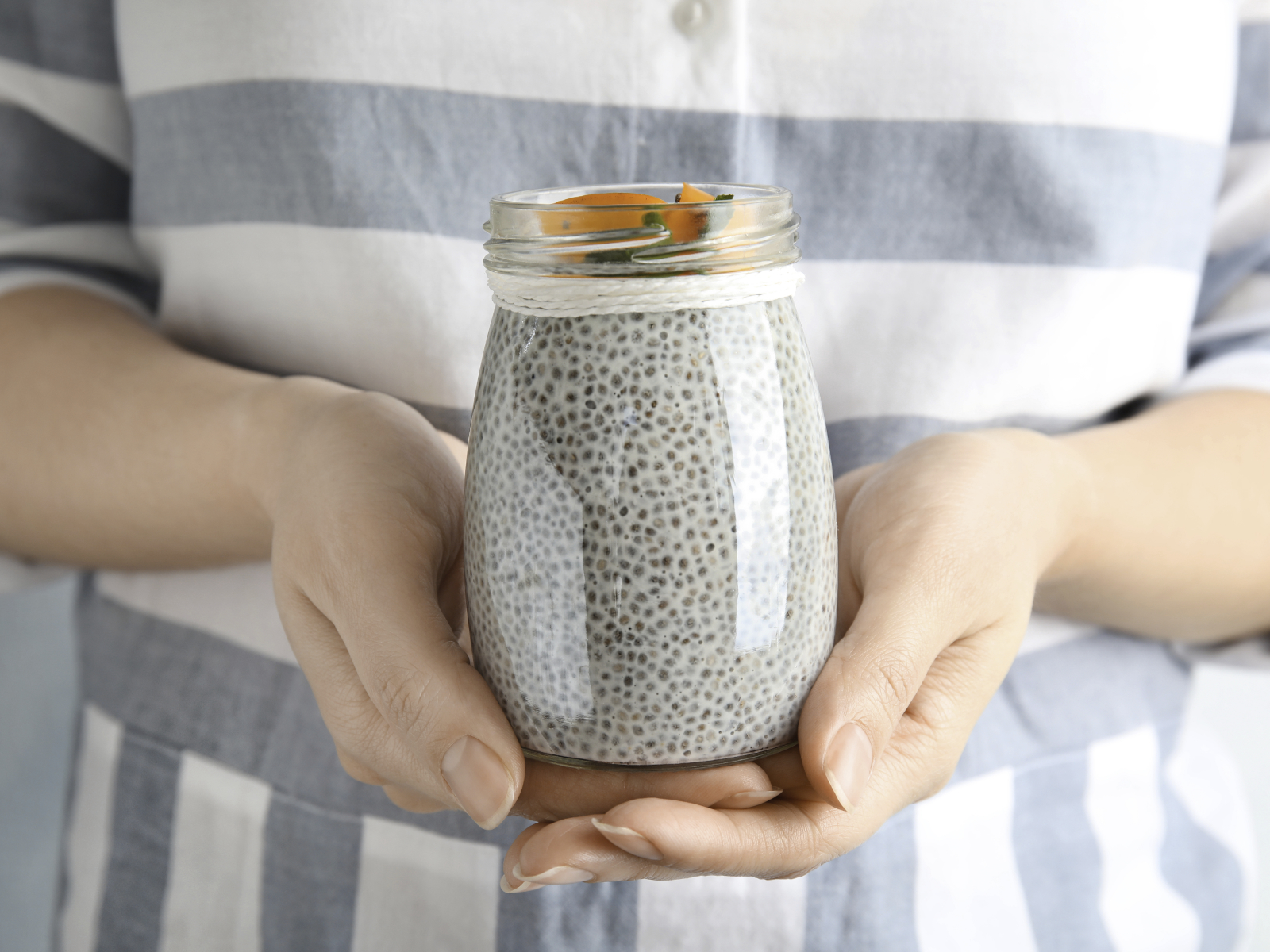 woman holding a jar of chia seed pudding with fruit