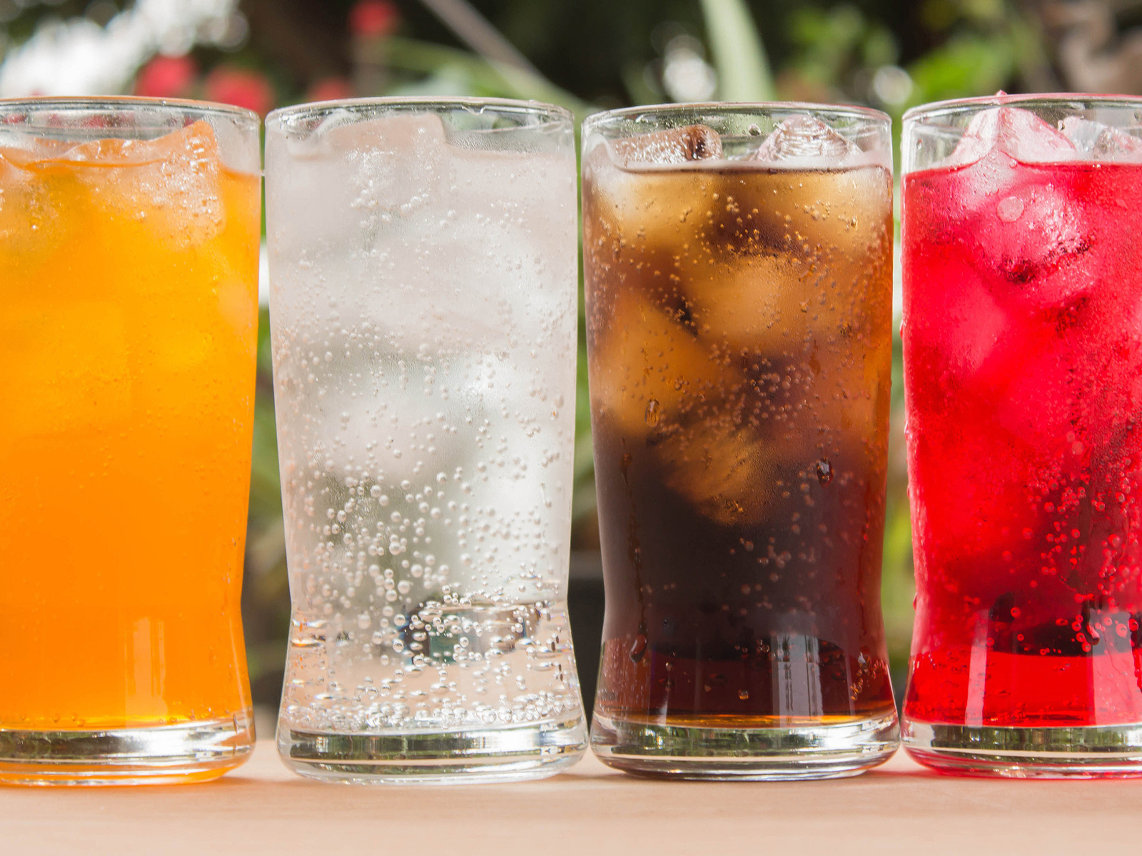 four glasses of different kinds of soda