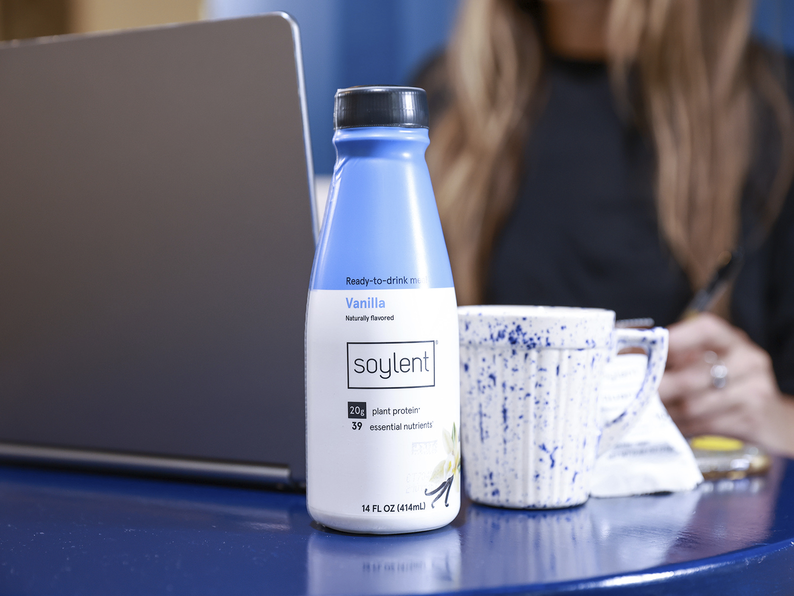 woman working with soylent bottle next to her