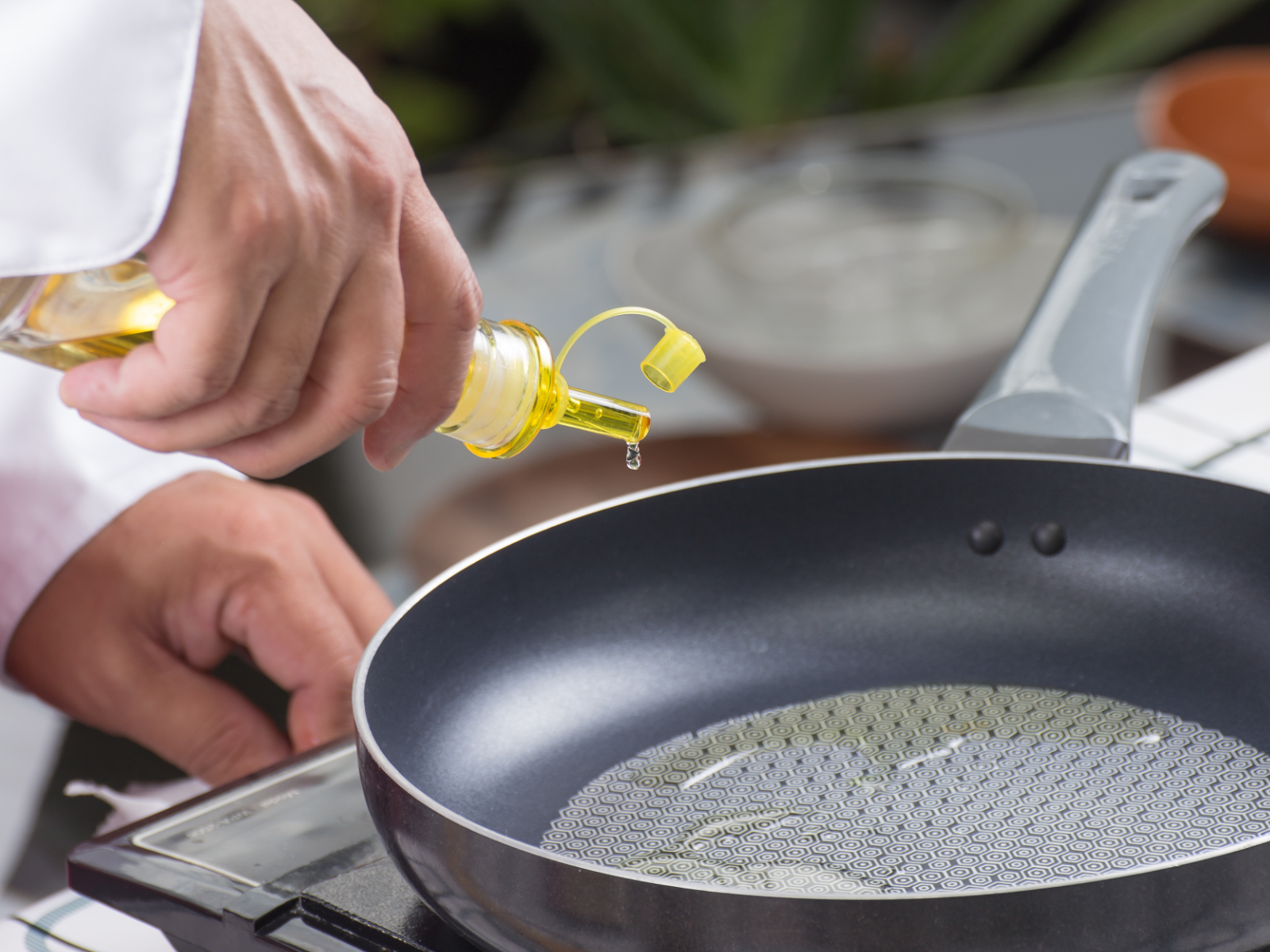 chef squeezing olive oil onto a pan