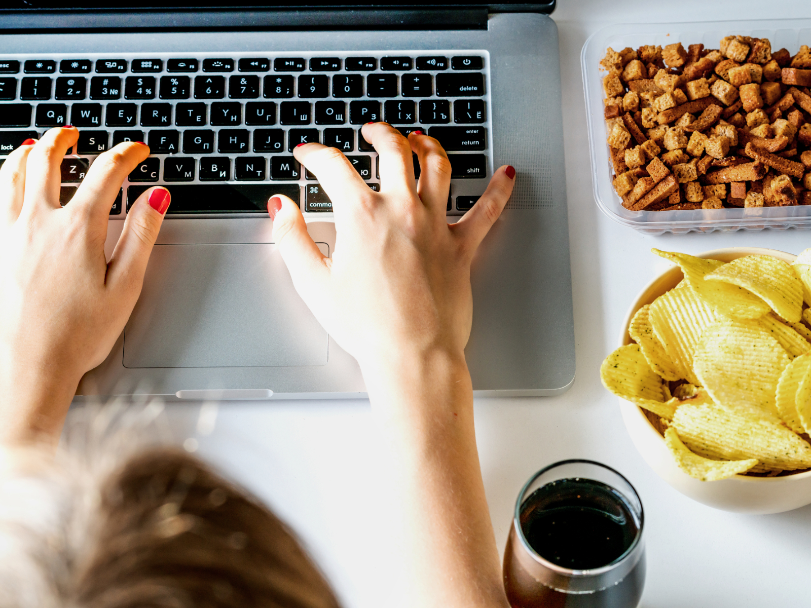 person typing on a laptop stressed next to snack foods