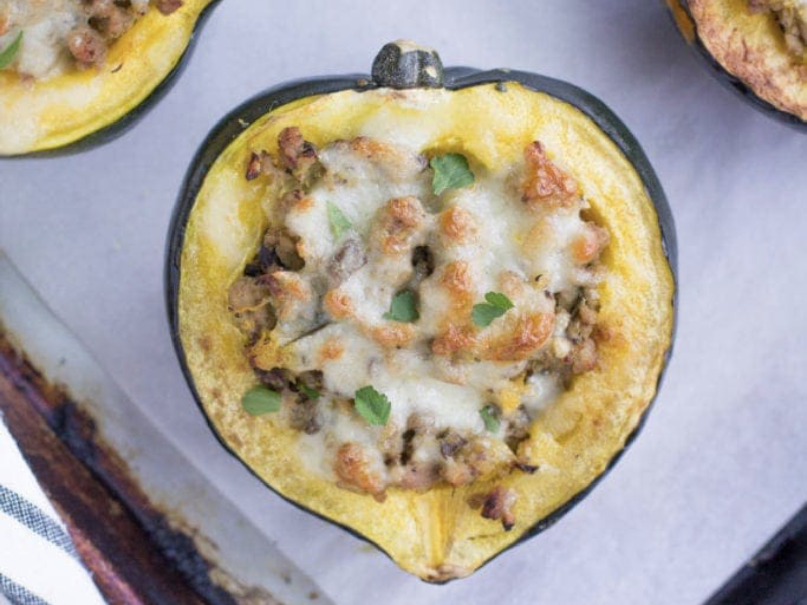 stuffed acorn squash on a sheet pan with melty cheese on top