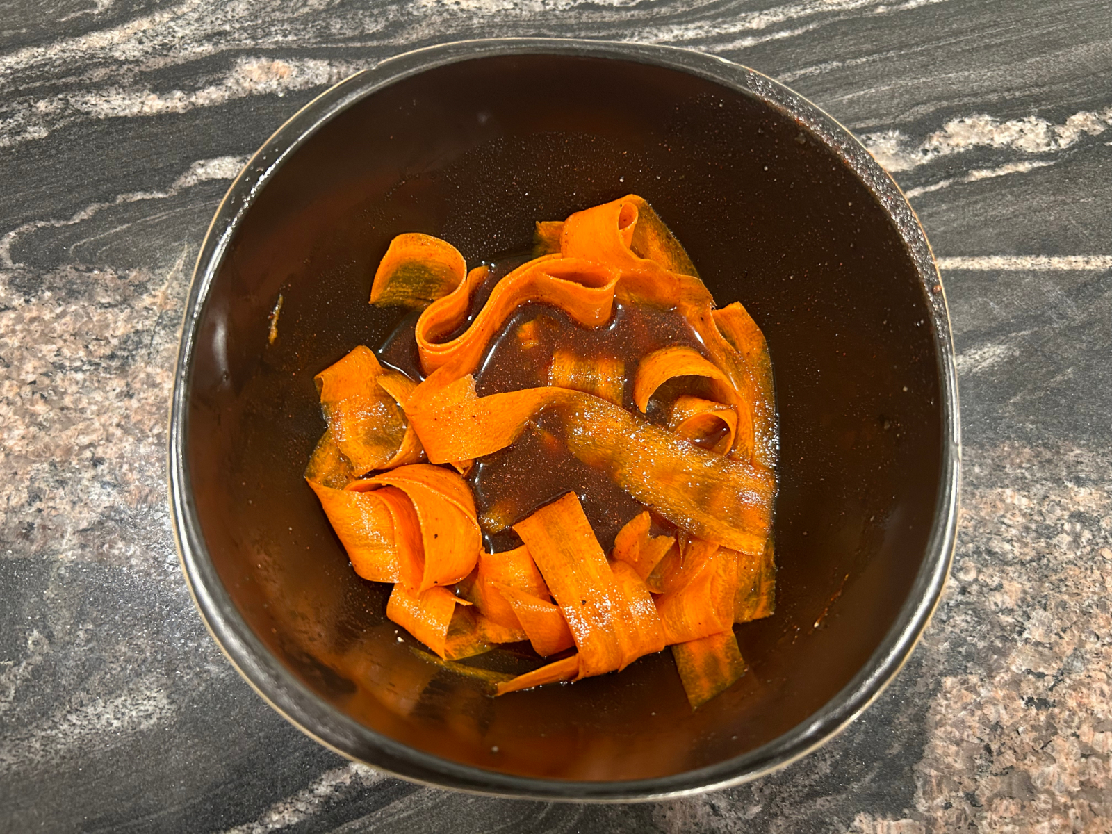 thin slices of carrot in a bowl to make carrot bacon